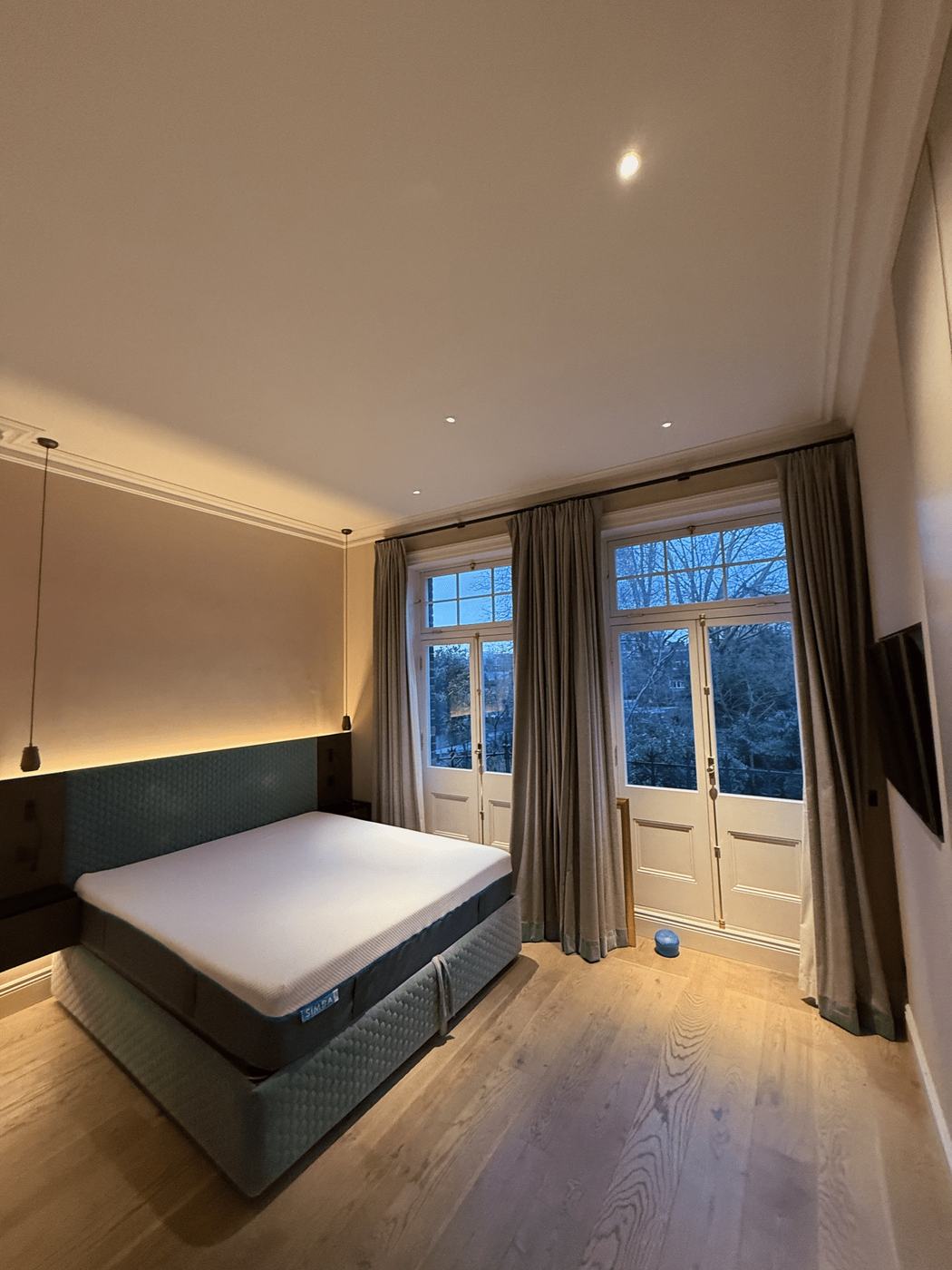 A calm bedroom with warm lighting and tall glazed doors