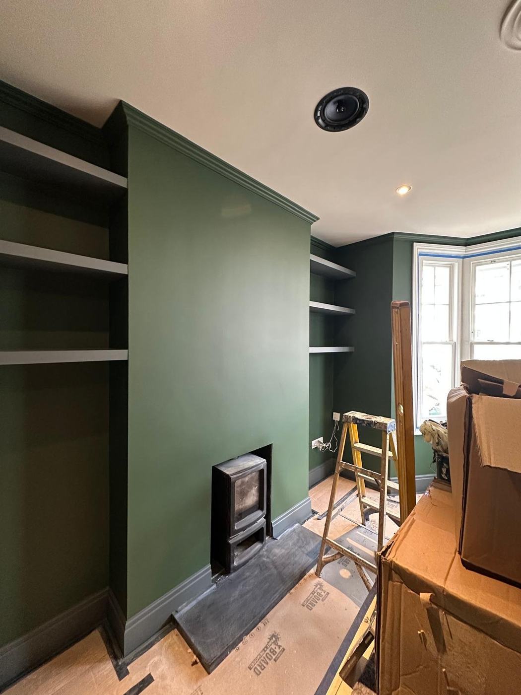 A deep green alcove and fireplace wall during decoration