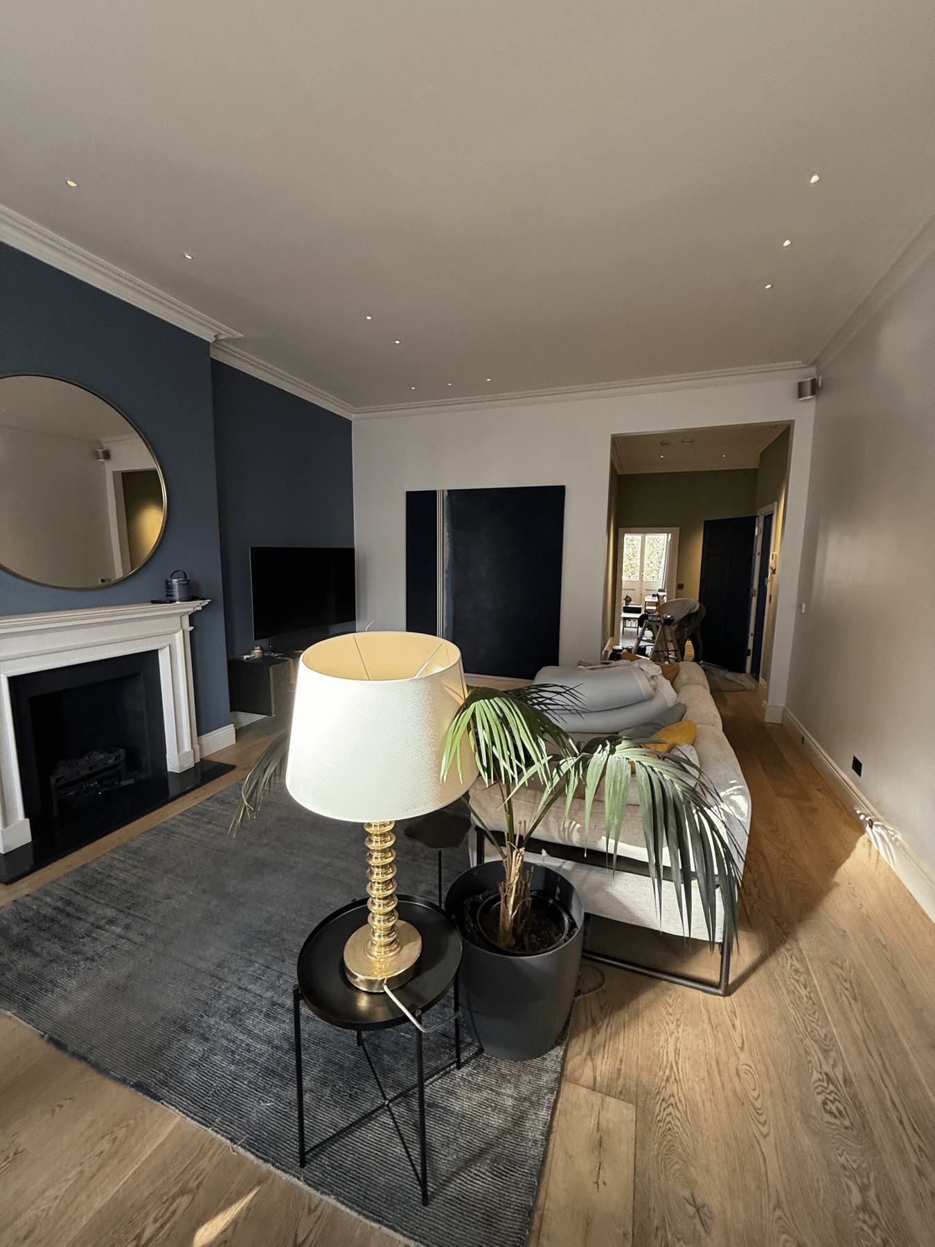 A lounge with a deep blue wall, white fireplace and oak floor