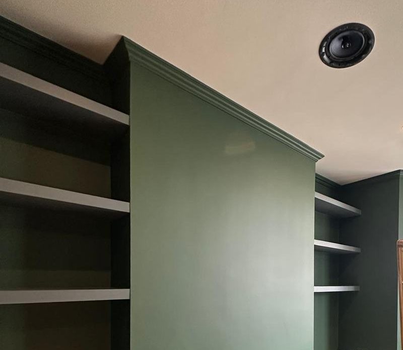 A chimney breast, coving and alcove shelves painted deep green
