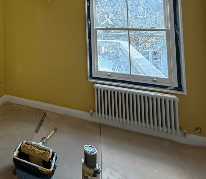 A room with mustard walls around a white sash window