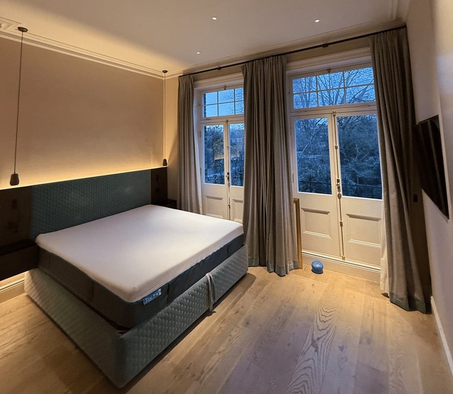 A bedroom with warm neutral walls and tall glazed doors