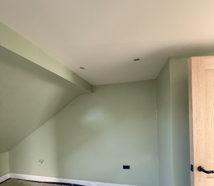 A room with sage walls and a sloping ceiling