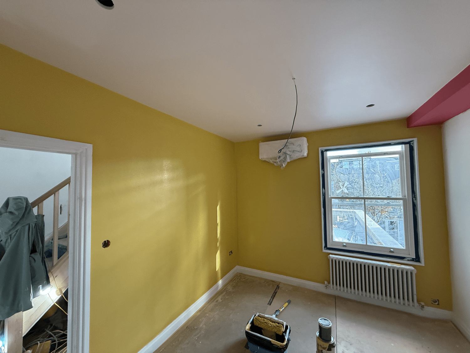 A room painted mustard yellow with a sash window