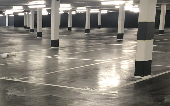 A glossy coated car park floor with painted columns and bay lines