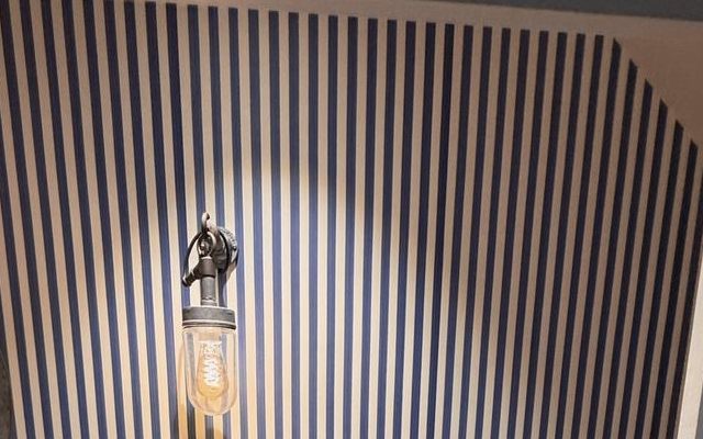 A cloakroom wall papered in bold blue and white vertical stripes
