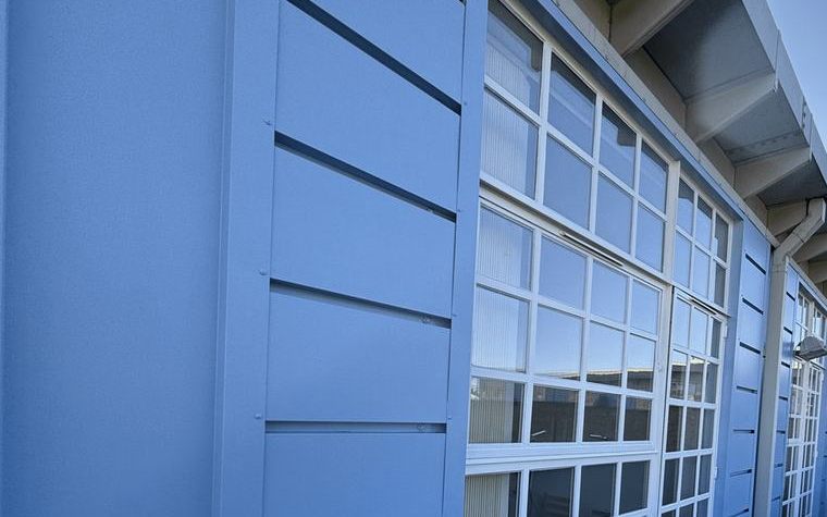 Bright blue metal cladding and window frames with an even painted finish