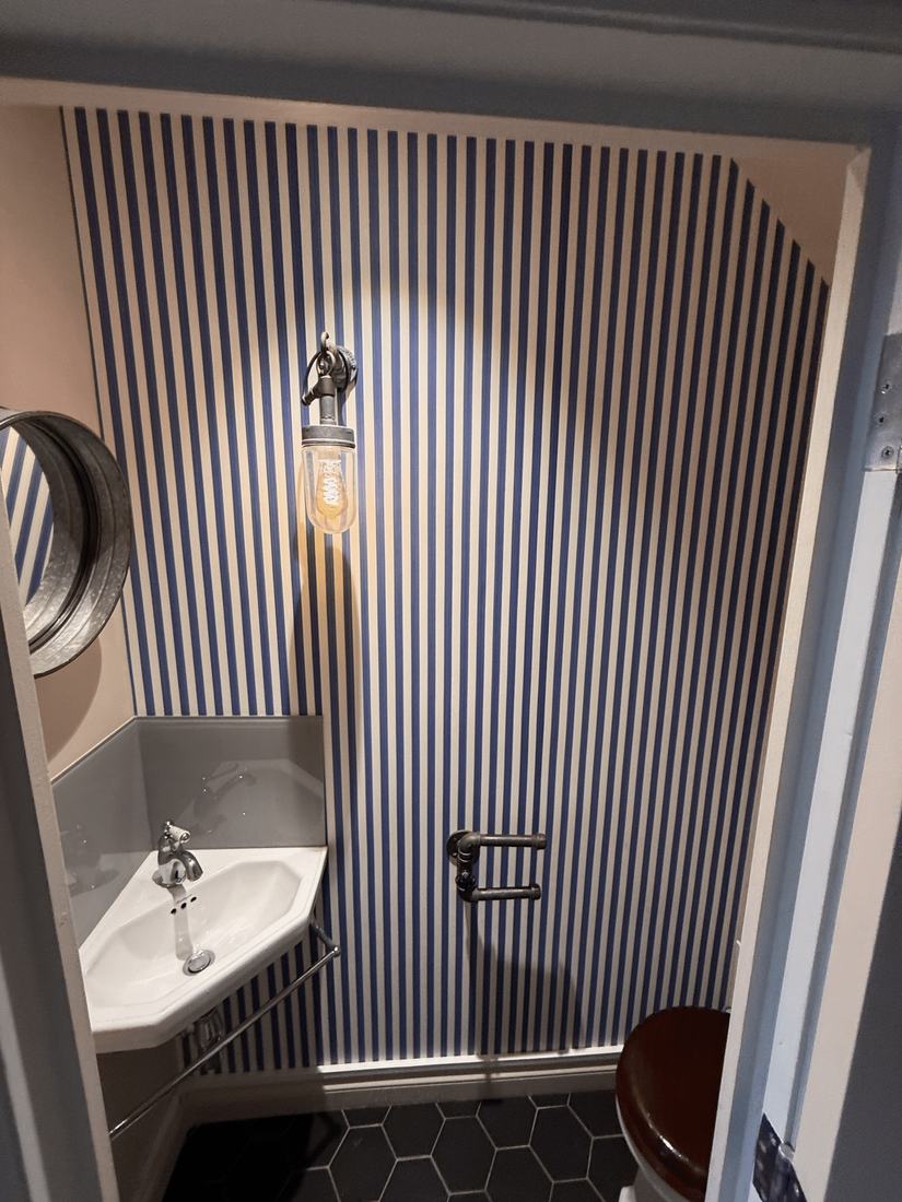 A cloakroom papered in bold vertical stripes