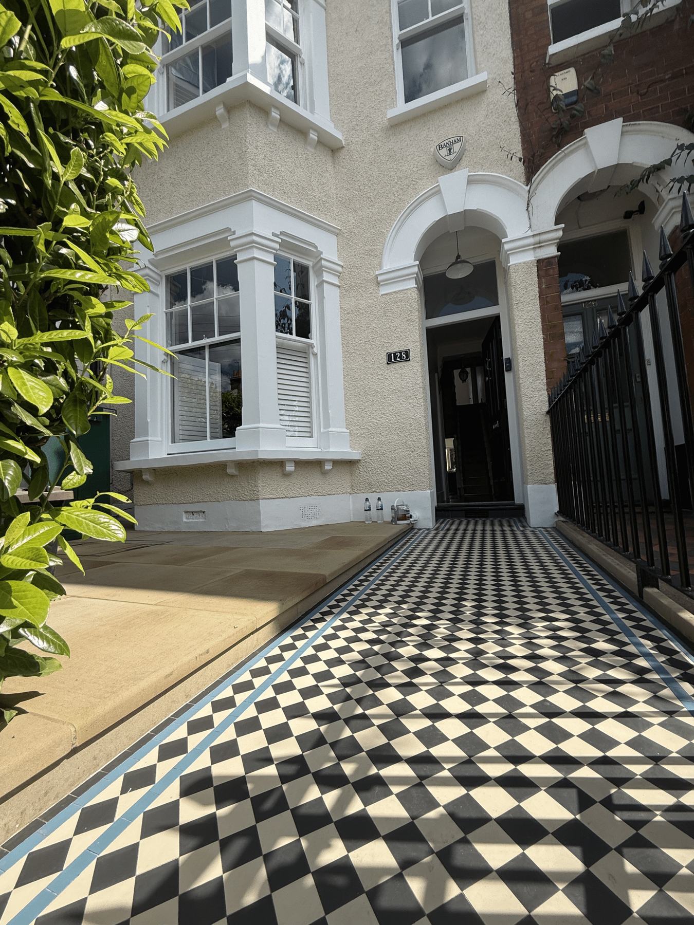 A chequered Victorian tiled path leading to a freshly painted front door