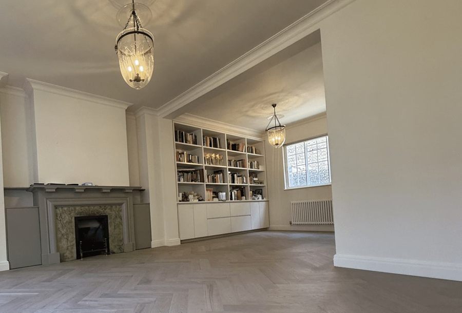 A bright living room with a herringbone floor, fireplace and built-in shelves