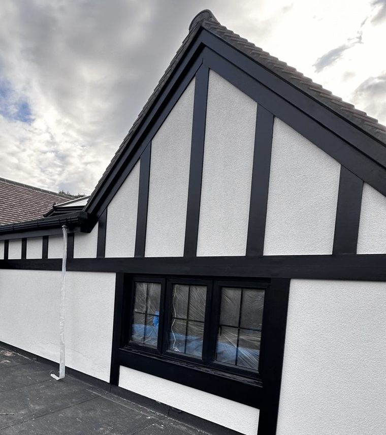 A freshly painted house with black and white Tudor-style gables